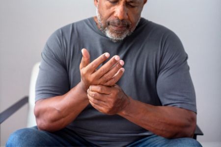 man seated massaging his painful hand