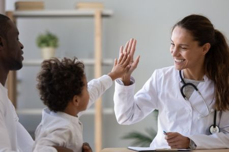 female doctor giving high five to young make patient