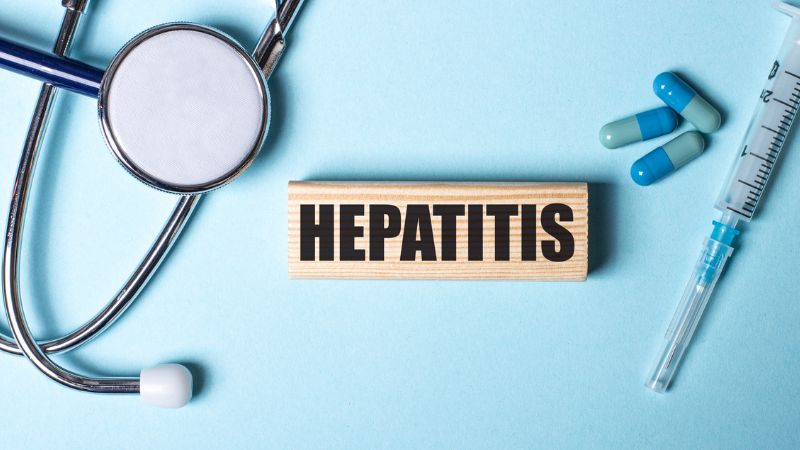 "Hepatitis" written on a block of wood between a stethoscope and needle