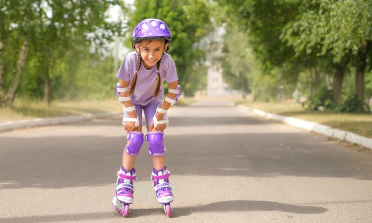 girls roller skating in matching purple outfits and safety pads